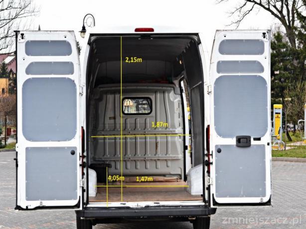Wnętrze furgonetki z otwartymi drzwiami z tyłu, z naniesionymi wymiarami przestrzeni ładunkowej.