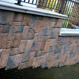 Elewacja zewnętrzna budynku wykończona kamieniem ozdobnym Incana Nevada ułożonym w diagonalny wzór, zwieńczona jasnoszarym gzymsem i czarną metalową balustradą.