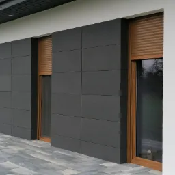 Nowoczesna elewacja budynku z szarymi panelami kwadratowymi, drewnianą stolarką okienną i częściowo opuszczonymi roletami zewnętrznymi w kolorze drewna, na tle kostki brukowej.