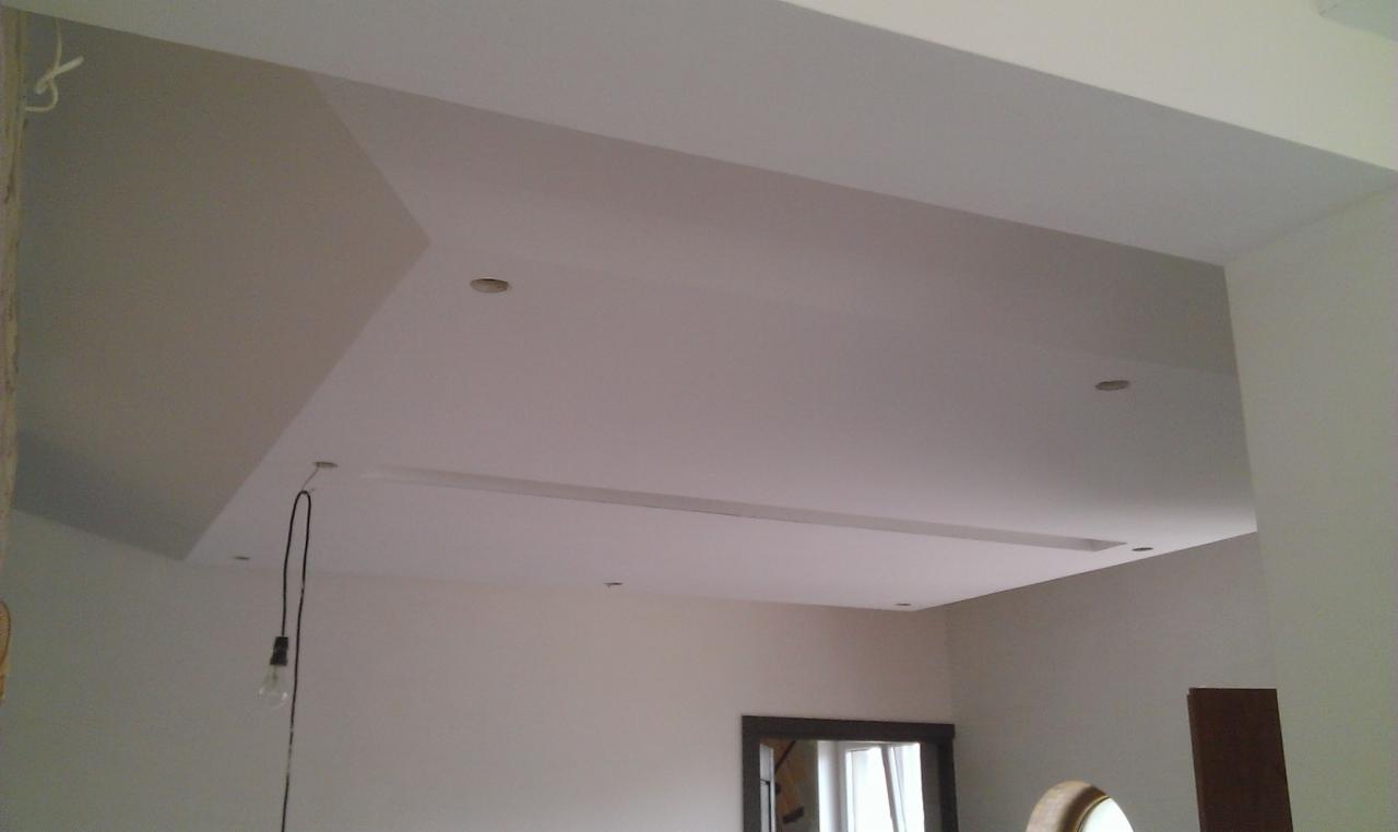 Nowoczesny sufit podwieszany z oświetleniem punktowym i listwą LED, świeżo po malowaniu, z widocznym wystającym przewodem żarówki.