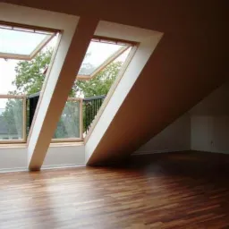 Jasne poddasze z drewnianą podłogą i dwoma skośnymi oknami dachowymi wychodzącymi na balkon z czarną balustradą i zielenią na zewnątrz.