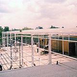 Szkielet konstrukcji z białych, stalowych profili na placu budowy, widok z góry, słabe oświetlenie.