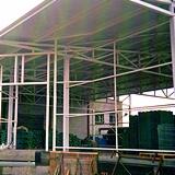 Szkielet hali w trakcie budowy, widoczne elementy konstrukcji stalowej i stos płyt warstwowych w tle.