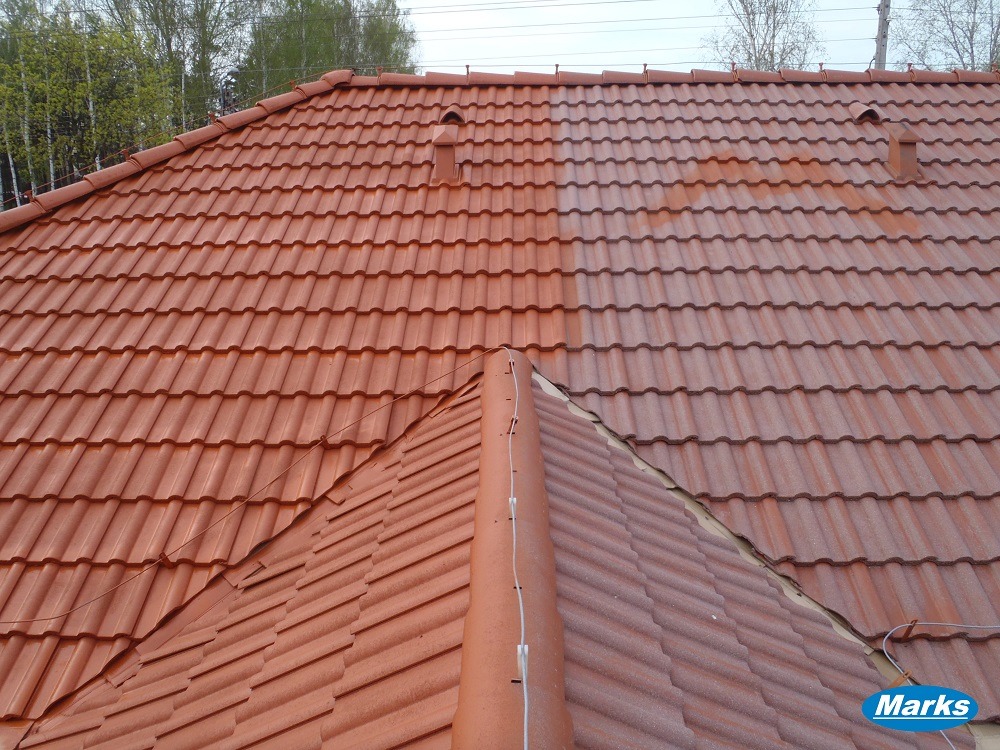 Częściowo umyty dach z czerwonej dachówki karpiówki, widoczne różnice w kolorze, zarys drzew w tle. Dach po lewej stronie jest czysty, po prawej brudny.
