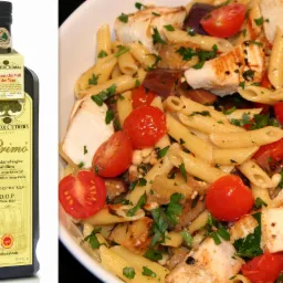 Elegancka butelka oliwy Frantoi Cutrera Primo obok talerza makaronu penne z grillowanym kurczakiem, pomidorami i bakłażanem. Całość skropiona oliwą z oliwek.