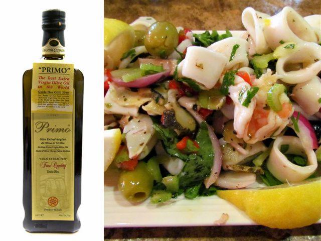 Butelka oliwy z oliwek Primo obok talerza sałatki z kalmarów, oliwek, cebuli i cytryny. Zdjęcie z bliska, ostre światło, widoczne detale składników.