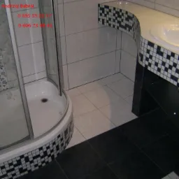 Wykończona łazienka z kabiną prysznicową i umywalką z szafką, wyłożona biało-czarnymi płytkami w szachownicę.