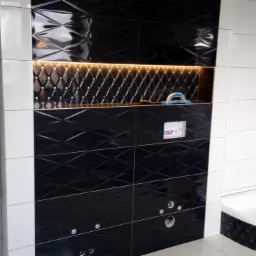 Częściowo wykończona łazienka z czarno-białymi płytkami diamentowymi, wnęką z oświetleniem LED i widocznymi otworami na armaturę.