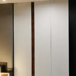 Biała szafa na wymiar z dekoracyjnymi pionowymi panelami w odcieniach bieli i brązu, oświetlenie punktowe sufitowe, pies rasy pitbull leżący na dywaniku u dołu kadru.