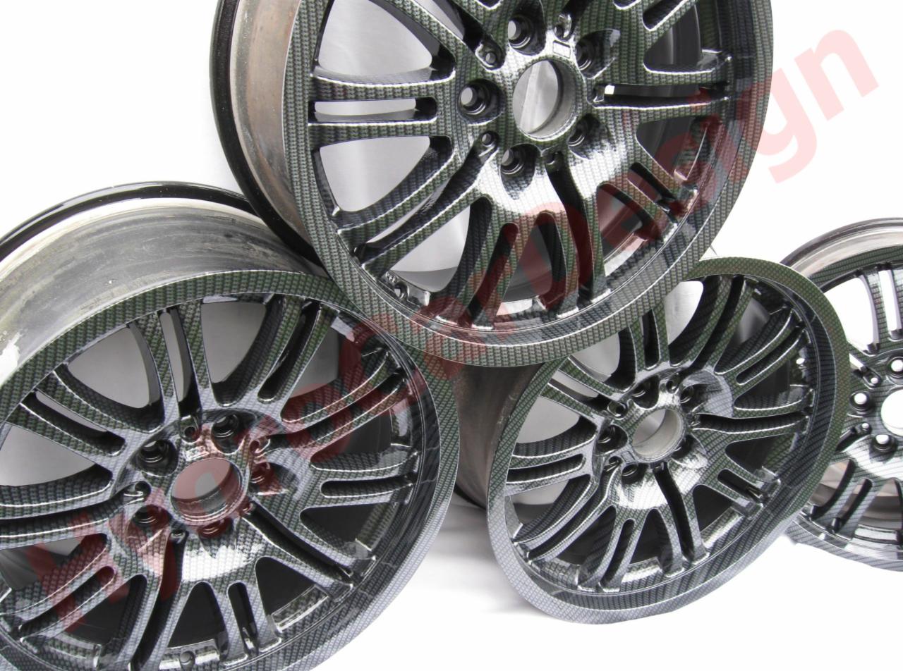 Cztery felgi samochodowe po hydrografice, z wzorem imitującym włókno węglowe, ułożone jedna na drugiej na białym tle.