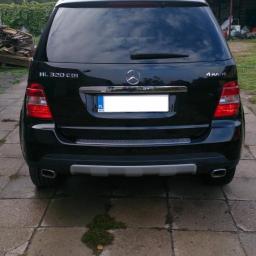 Diamentowy Blask - Czarny Mercedes ML 320 CDI 4MATIC, widok z tyłu na kostce brukowej z zielonymi porostami. Widoczne detale: relingi dachowe, tylne światła i chromowane wykończenia.