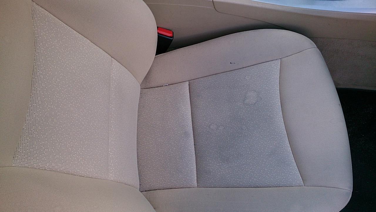 Beżowa tapicerka fotela samochodowego z plamami, wymagająca odświeżenia. Usługi prania tapicerki w Łodzi.