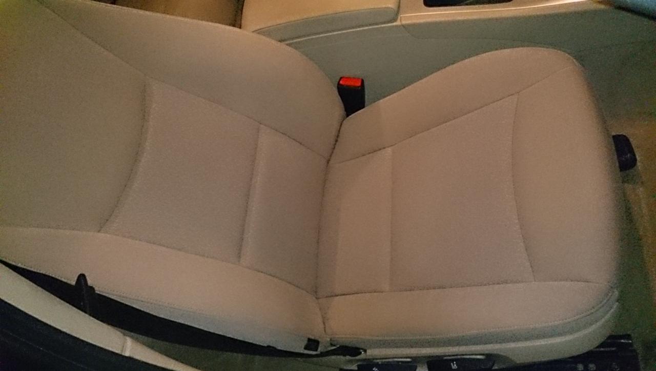 Jasne, skórzane siedzenie samochodowe z widocznym zagłówkiem i fragmentem deski rozdzielczej. Detal wnętrza auta po czyszczeniu.