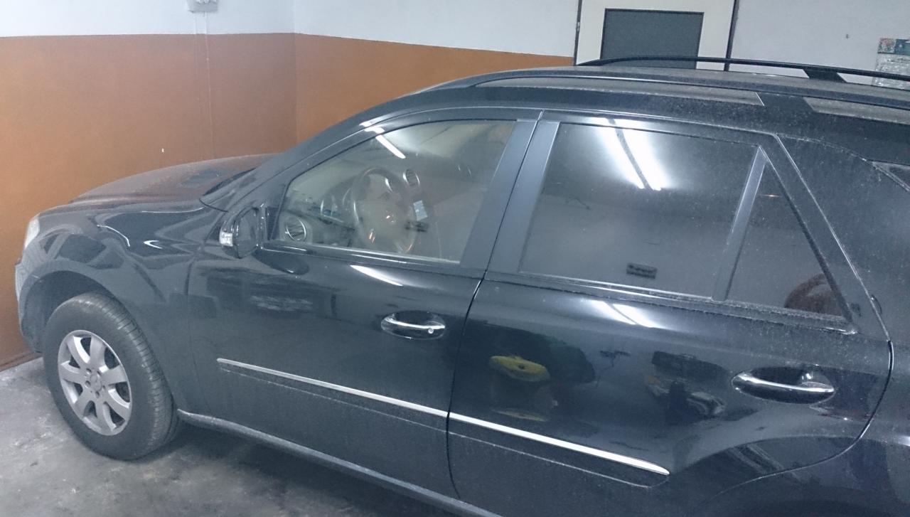 Brudny, czarny SUV Mercedes-Benz w garażu, wymagający umycia. Widoczne zacieki i kurz na karoserii, co sugeruje potrzebę skorzystania z usług myjni.