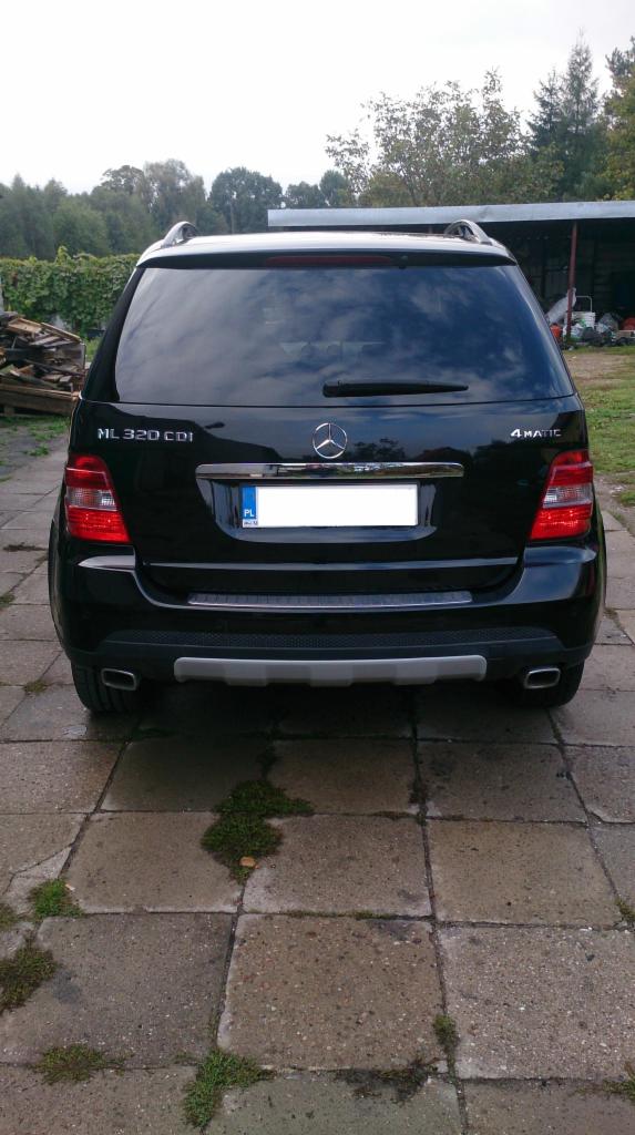 Czarny Mercedes ML 320 CDI 4MATIC, widok z tyłu na kostce brukowej z zielonymi porostami. Widoczne detale: relingi dachowe, tylne światła i chromowane wykończenia.
