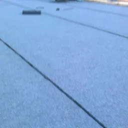 Szary, utwardzony teren z widocznymi liniami podziału, prawdopodobnie droga lub plac, w słabym oświetleniu.