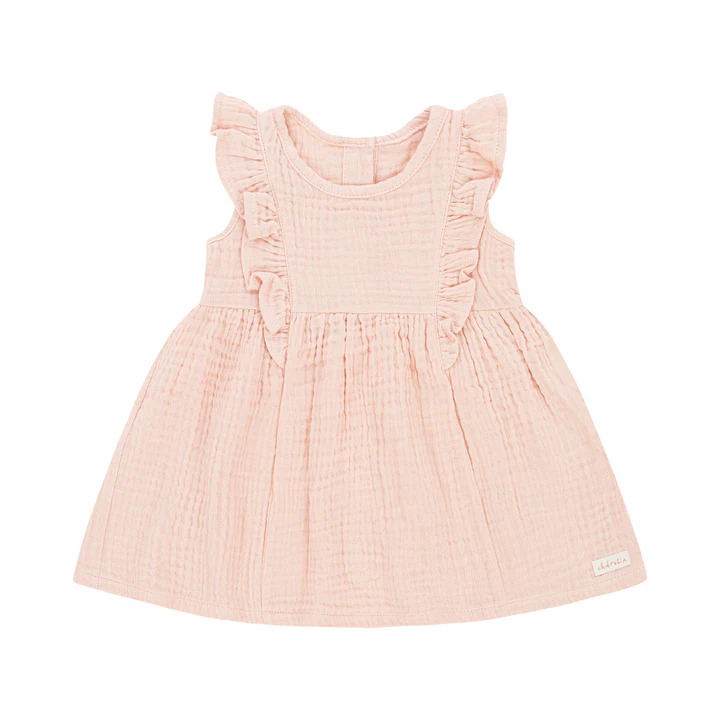 Delikatna, muślinowa sukienka dla niemowlaka w odcieniu pudrowego różu, z falbankami przy ramionach i subtelnym logo w dolnym rogu.