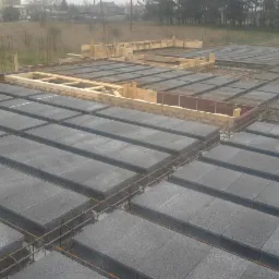 Wieniec stropowy Teriva z szalunkiem drewnianym i zbrojeniem na budowie domu jednorodzinnego; widok z góry na ułożone bloczki szalunkowe.