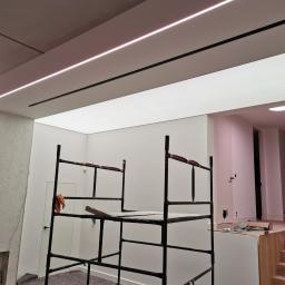 Firma ogólnobudowlana Grzegorz Groszek - Montaż sufitu podwieszanego z oświetleniem LED, widoczne rusztowanie i przygotowane podłoże.