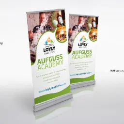 Dwa roll-upy reklamowe z logo Loyly Masters Aufguss Academy. Grafika przedstawia mężczyznę w saunie i informacje o szkoleniach z aromaterapii i ziołolecznictwa.