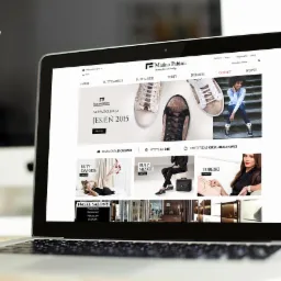 Laptop z otwartą stroną Marino Fabiani prezentujący nową kolekcję jesień 2015 z kategoriami: buty damskie, męskie, torby i dodatki. Widoczne logo i certyfikat oryginalności.