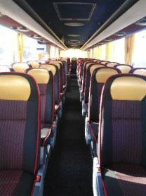 Wnętrze autobusu z rzędami foteli w kolorze bordowo-czarnym z żółtymi zagłówkami, widok z przodu na środek pojazdu, oświetlenie górne.