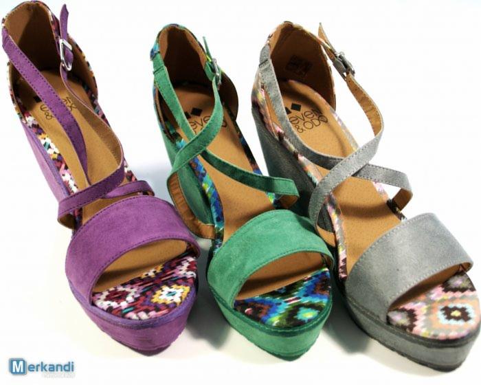 Trzy sandały na koturnie: fioletowe, zielone i szare, każdy z wzorzystą wkładką, ustawione obok siebie na białym tle.
