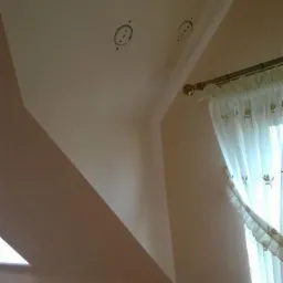 Poddasze po izolacji wdmuchiwanej, widoczne trzy otwory wentylacyjne w suficie skośnym, okno dachowe i zasłona w oknie.