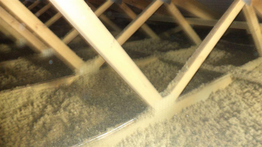 Wypełniona izolacją wdmuchiwaną przestrzeń poddasza z widocznymi drewnianymi elementami konstrukcyjnymi