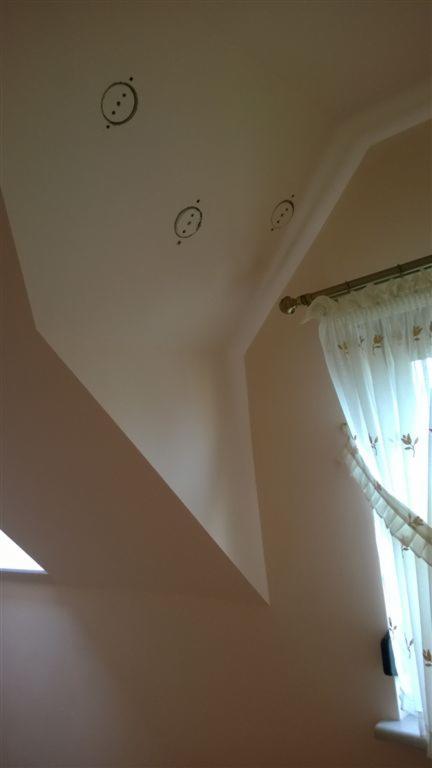 Poddasze po izolacji wdmuchiwanej, widoczne trzy otwory wentylacyjne w suficie skośnym, okno dachowe i zasłona w oknie.