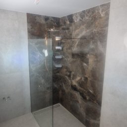 KBR Karol Reszka - Nowoczesna kabina prysznicowa typu walk-in z marmurowymi płytkami w odcieniach brązu i szarości. Minimalistyczny design, szklana ścianka działowa i odpływ liniowy.