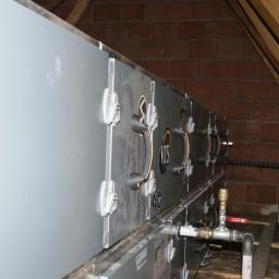 Cool System Systemy Wentylacji i Klimatyzacji - Instalacja rekuperacji VTS w przestrzeni poddasza z widocznymi elementami montażowymi, rurami i drewnianą konstrukcją dachu.