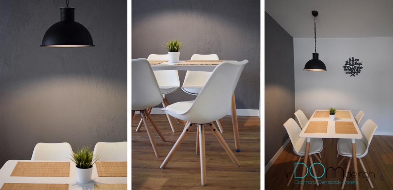 Nowoczesna jadalnia z białym stołem, krzesłami Eames i czarną lampą wiszącą, akcentowana geometrycznym zegarem na ścianie.