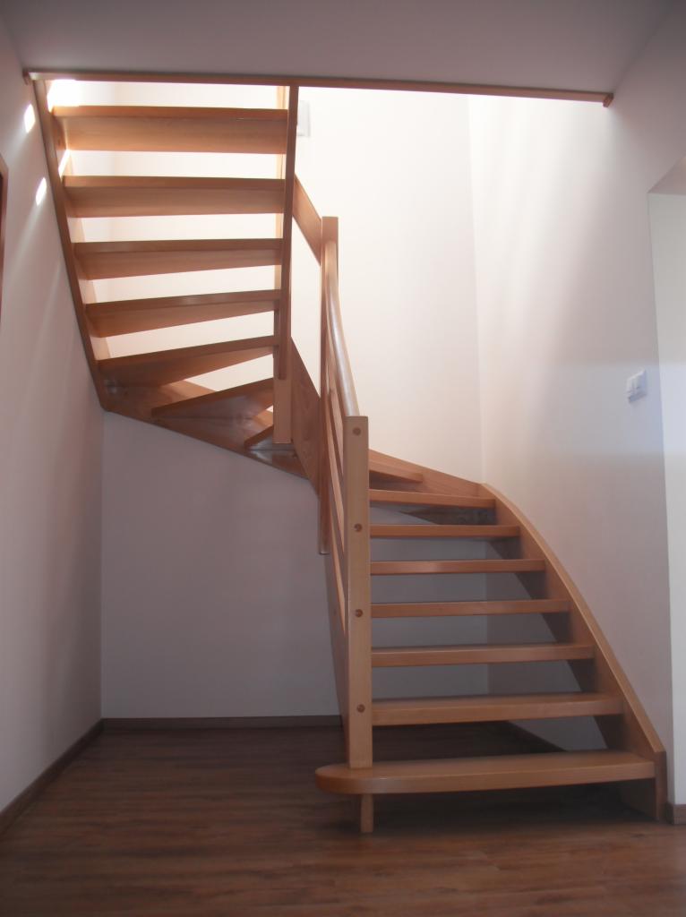 Drewniane schody kręcone z jasnego drewna z poręczą, zamontowane w domu w Nowej Rudzie, z widocznym oświetleniem górnym.