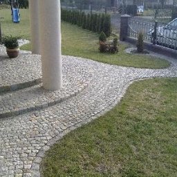 BRUK-MED Kamil Grądziel - Granitowa ścieżka z kostki prowadząca od schodów domu do furtki, otoczona trawnikiem i niskimi tujami.