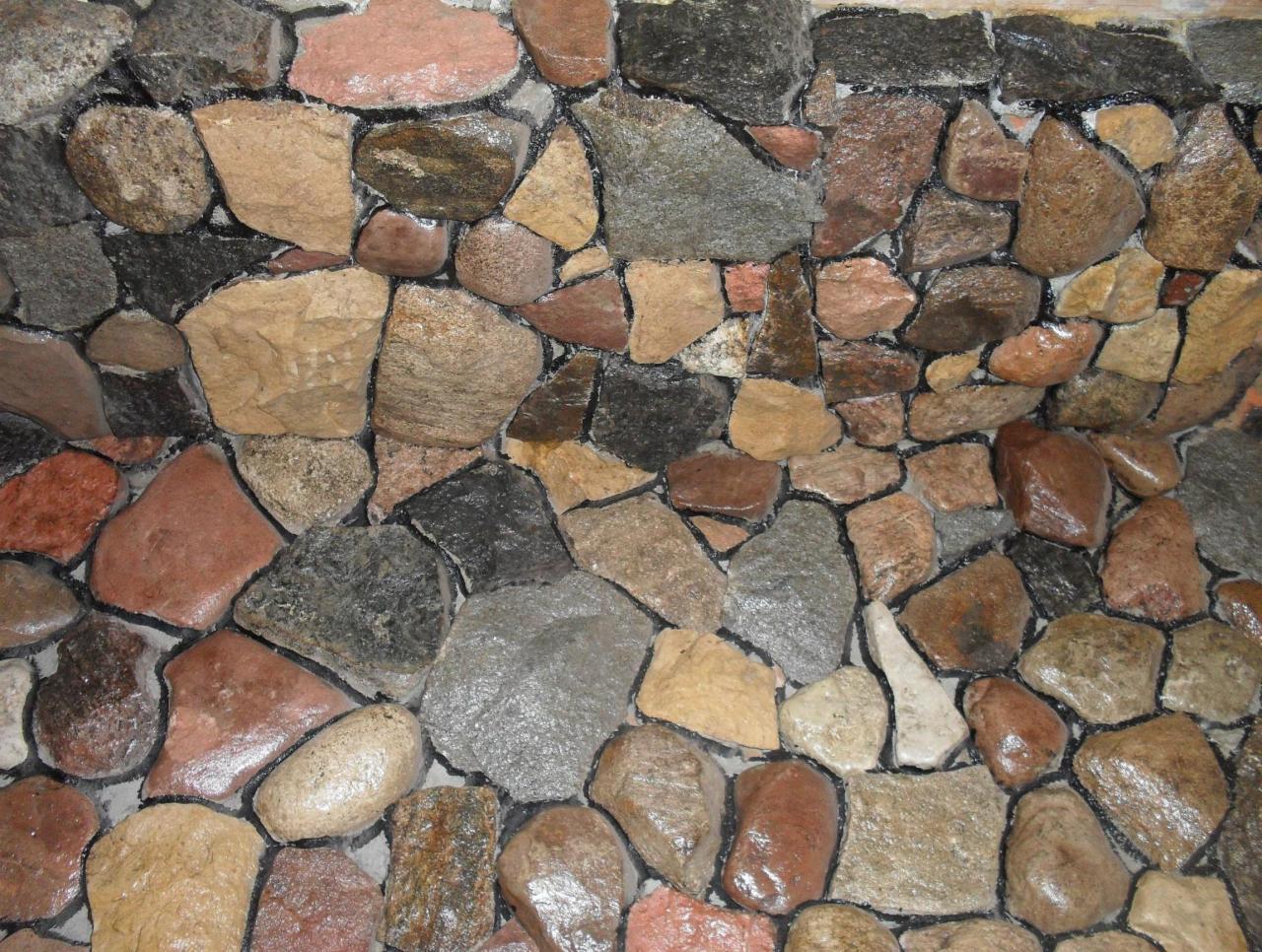 Fragment ogrodzenia z kamienia naturalnego w miejscowości Prostyń, z widoczną różnorodnością kolorów i faktur kamieni.