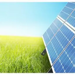 Panel słoneczny na tle zielonego pola i błękitnego nieba z promieniami słońca, ujęcie z niskiej perspektywy.