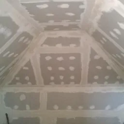 Skośne poddasze z płytami gipsowo-kartonowymi, wstępnie wyszpachlowane łączenia i wkręty, surowe wykończenie poddasza, kabel na podłodze.