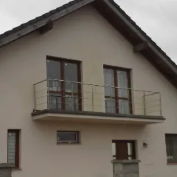 Nowoczesna balustrada balkonowa ze stali nierdzewnej, z poziomymi prętami, zamontowana na balkonie domu o jasnej elewacji i brązowych oknach, widok z dołu.