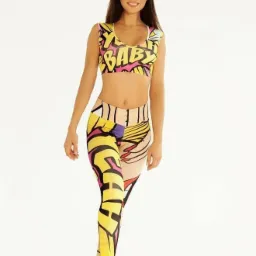 Kobieta prezentuje komplet sportowy: krótki top i legginsy z nadrukiem w stylu komiksowym, na białym tle.