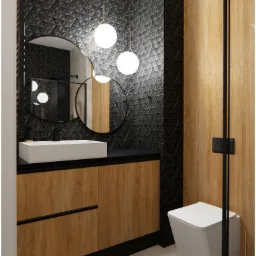 Nowoczesna łazienka z czarnymi, trójwymiarowymi płytkami, drewnianą szafką pod umywalką i okrągłym lustrem podświetlonym trzema kulistymi lampami.