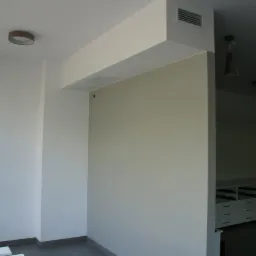 Wnętrze po malowaniu w Tomaszowie Mazowieckim. Ściany w jasnych odcieniach, widoczna drabina malarska i fragment zabudowy meblowej w głębi pomieszczenia.