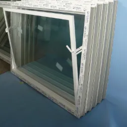 Białe, uchylne okno PCV marki GEALAN, z widocznym mechanizmem otwierania, ustawione obok innych okien, gotowe do montażu.