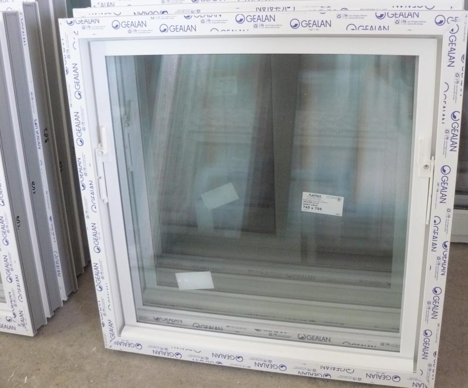 Białe okno z ramą Gealan, widoczne etykiety z rozmiarem 745x755, ułożone obok innych okien, oświetlenie dzienne, widok z bliska.