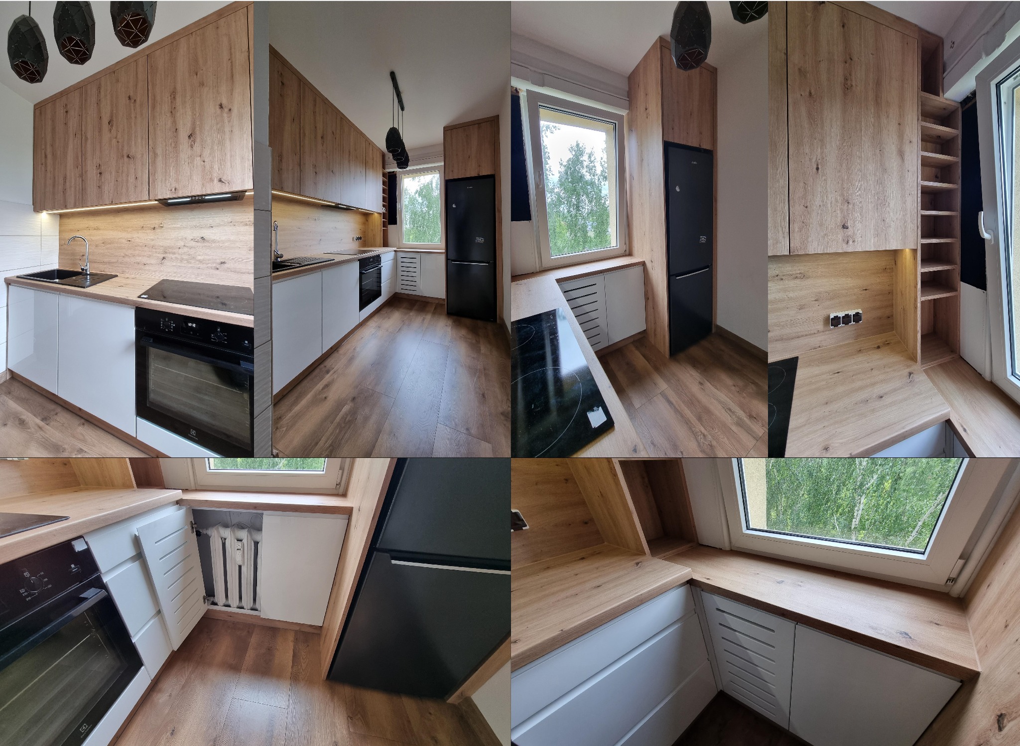 Nowoczesna kuchnia z białymi frontami i drewnianymi blatami. Widok na okno, czarna lodówka i płyta indukcyjna. Uwagę zwraca zabudowa grzejnika i oświetlenie LED.