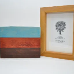Drewniana ramka na zdjęcie z grafiką drzewa, obok trzy ułożone deseczki pomalowane na niebiesko, brązowo i ciemnobrązowo.