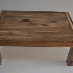 Prostokątny stolik kawowy z drewna orzechowego z widocznymi słojami i naturalnymi sękami, z jasnym paskiem wzdłuż krawędzi blatu, na tle białej ściany.