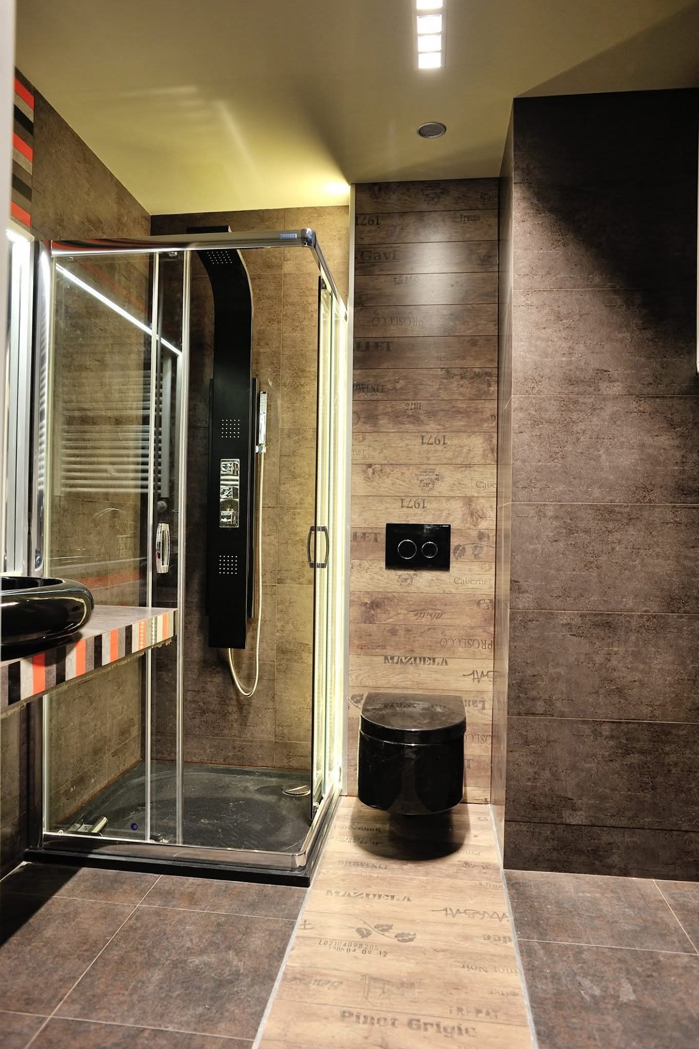 Nowoczesna łazienka z kabiną prysznicową typu walk-in, czarną armaturą i płytkami imitującymi drewno z napisami. Minimalistyczny design, oświetlenie LED.