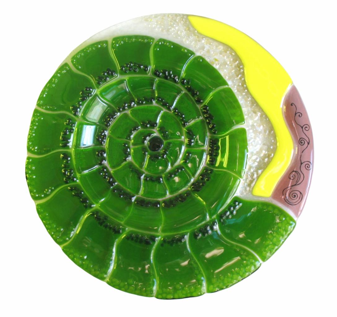Dekoracyjny talerz ze szkła artystycznego, z motywem zielonego spiralnego wzoru i elementami w kolorach żółtym, brązowym i białym na białym tle.