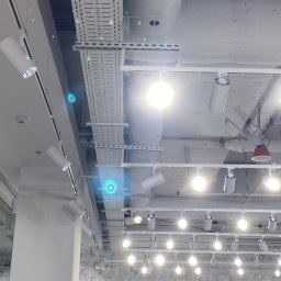 ELMAR TECHNOLOGY SPÓŁKA Z OGRANICZONĄ ODPOWIEDZIALNOŚCIĄ - Białe, nowoczesne oświetlenie punktowe na szynoprzewodach pod sufitem w sklepie, widoczne koryta kablowe i instalacje sufitowe.